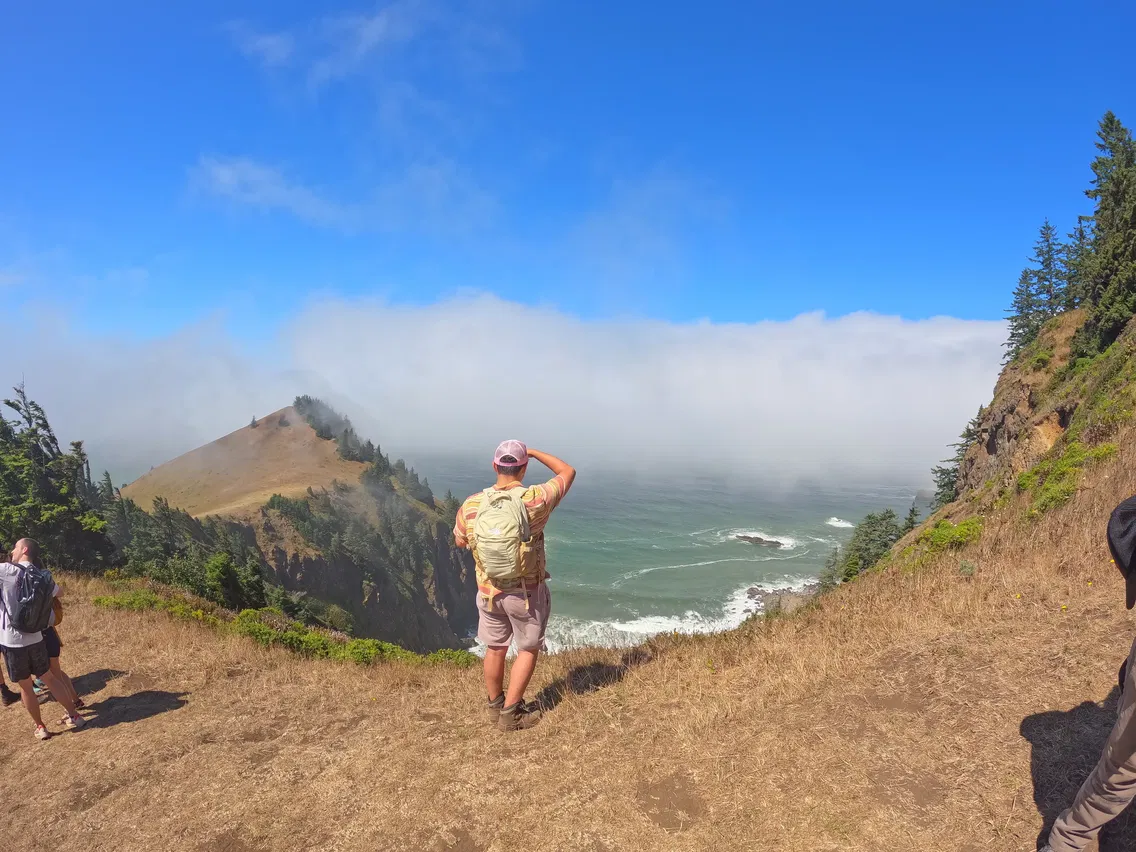 People standing on top of a hill that overlooks the clouds and the mountains near the Oregon coastline