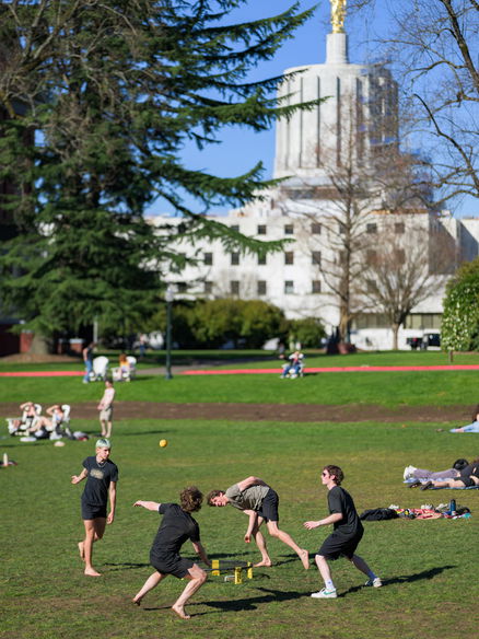 Students at Willamette University playing frisbee in the quad; state Captiol building in the background