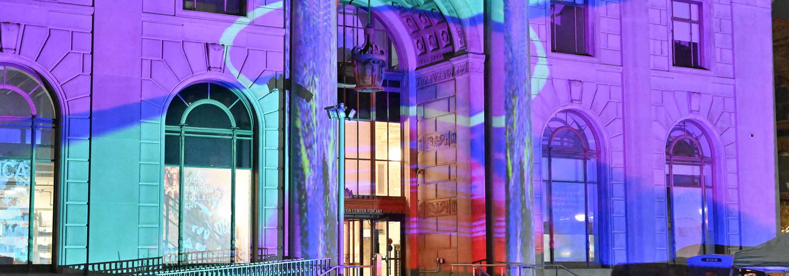 Building exterior with colorful lights projected on it.