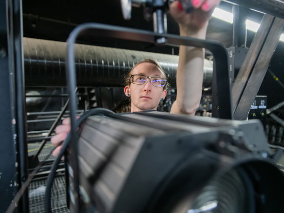 A Willamette Theatre student adjusts lighting above the stage