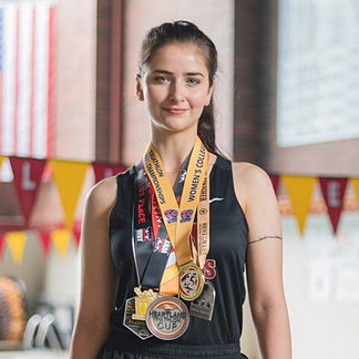 Veronica Castille standing in front of the Willamette University pool with metals around their neck