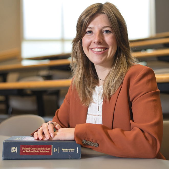 Professional shot of Madeline Hueske sitting in Willamette Law with a school book on the desk