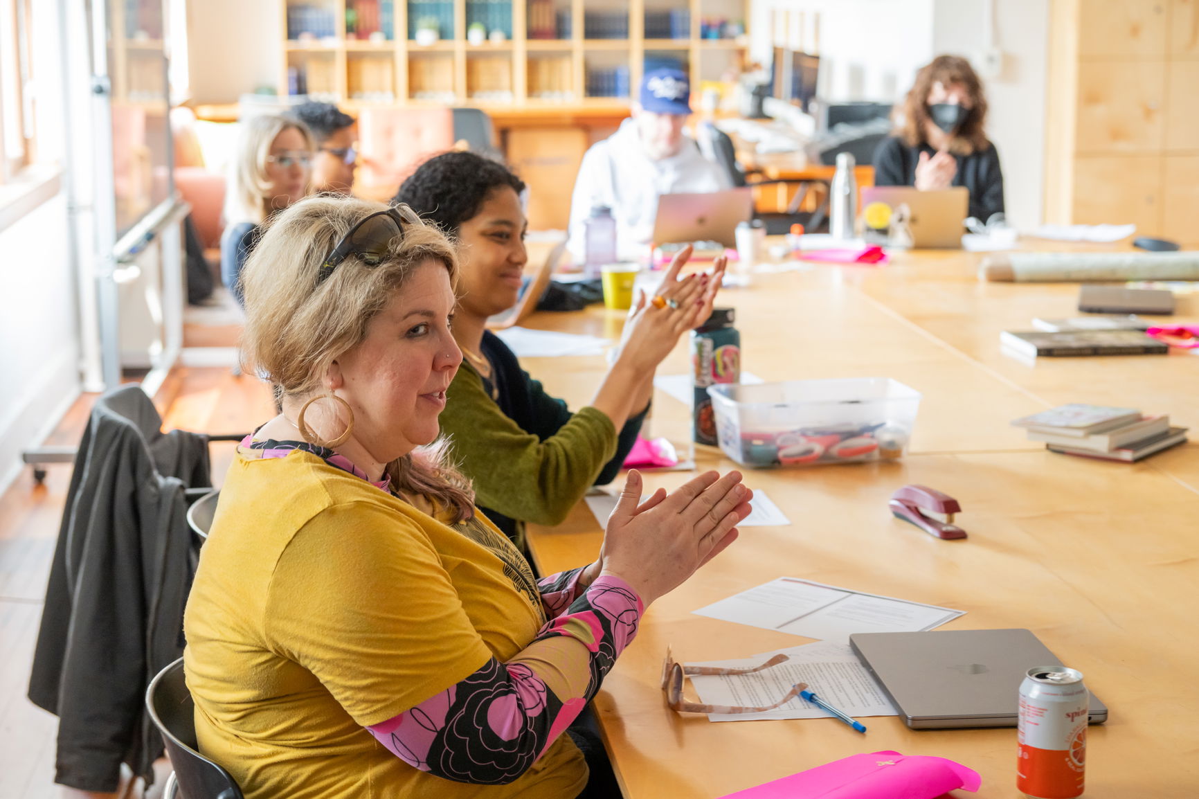 A classroom of students sitting with their hands together above the table.