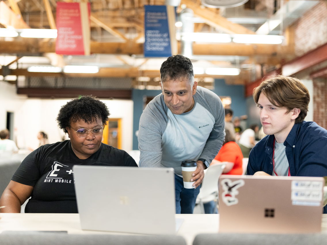 Three people discussing something on a laptop at Willamette