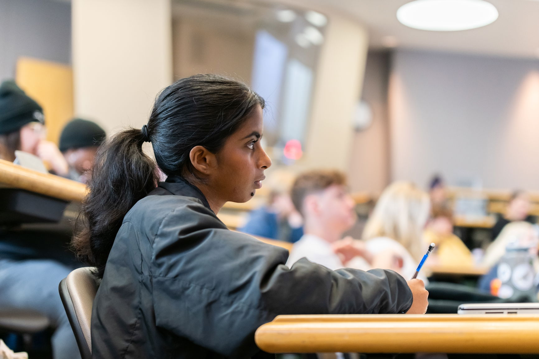 A close up of a student in a classroom taking notes