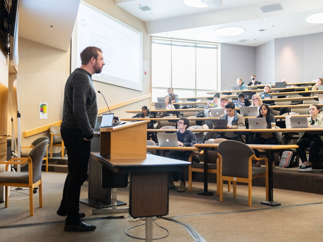 A law professor giving a lecture in a classroom in front of a podium