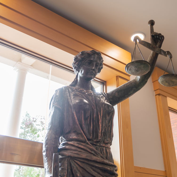 A bronze statue of lady justice near windows