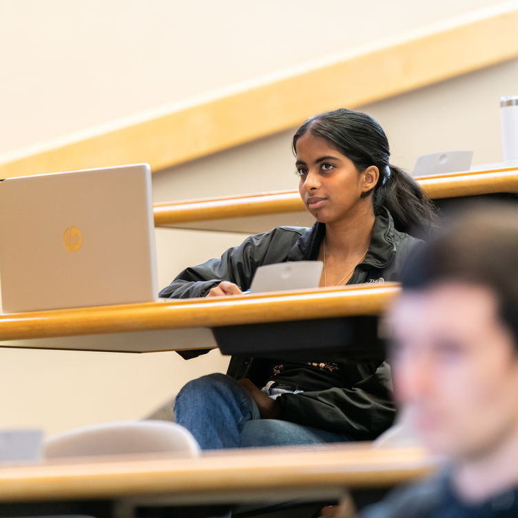 A student sitting within a classroom focused on the lecture