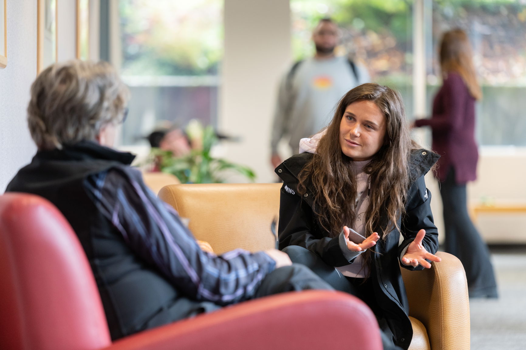 A student speaking to a law professor in chairs that are side by side