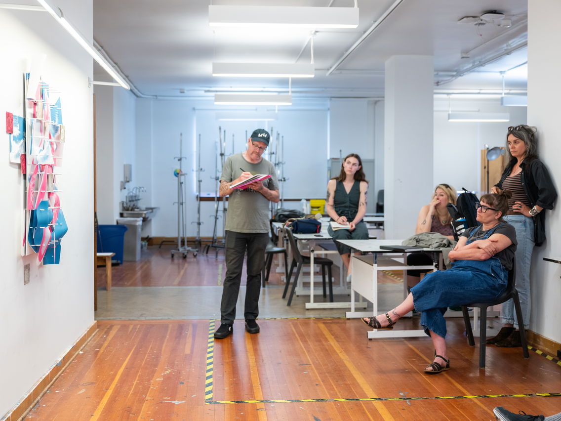 Students analyzing art on a wall in a well-lit classroom