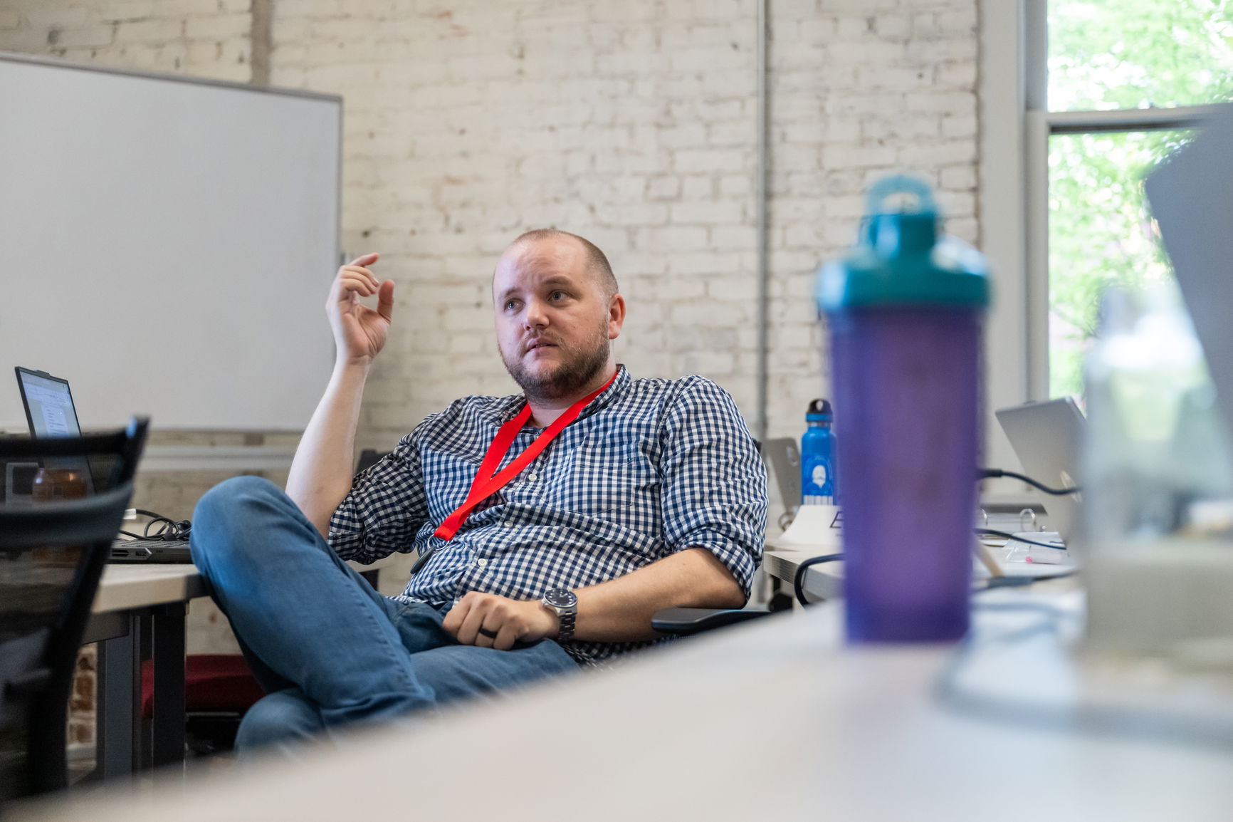 A male in a blue shirt sitting in a brick classroom