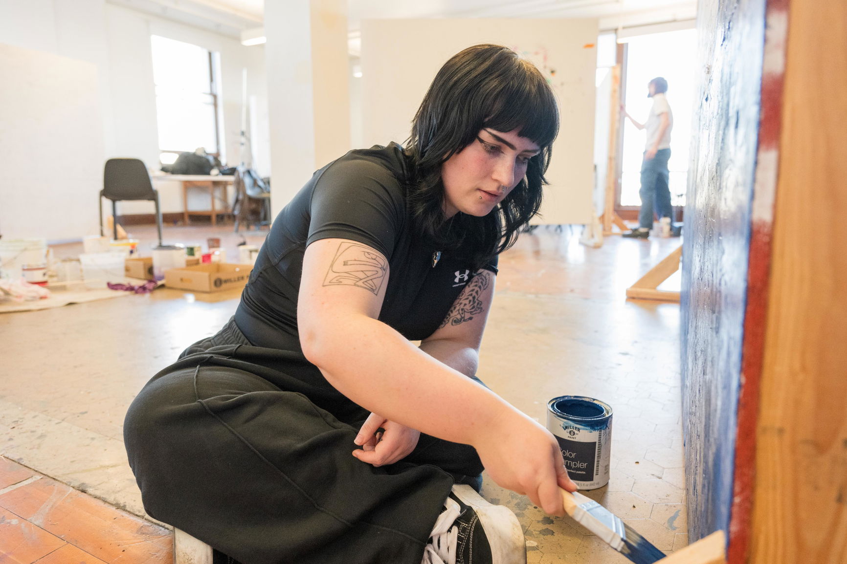 A student sitting on the floor and painting.