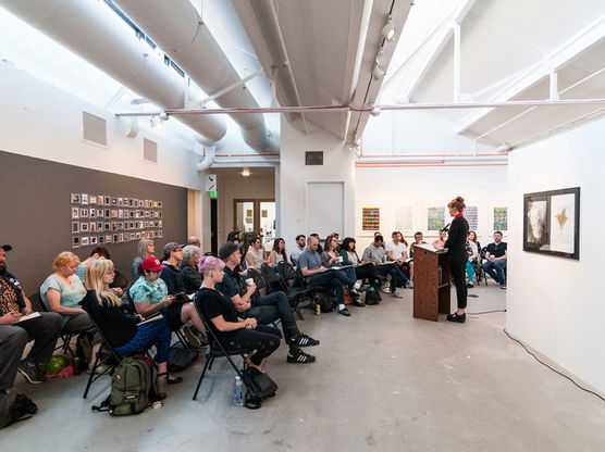 A student presenting their thesis to a full room of people