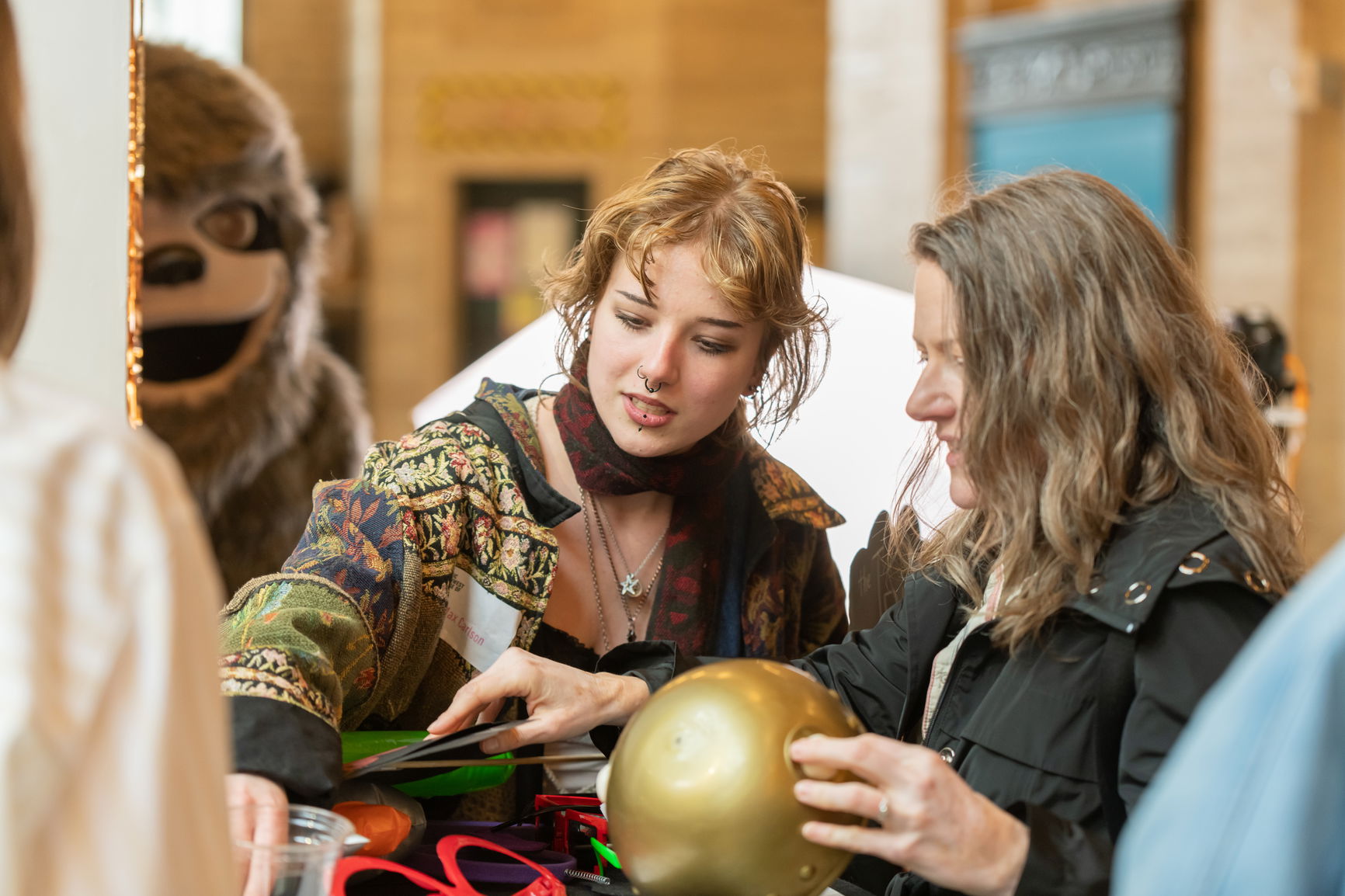 A person inspecting a golden ball with another person