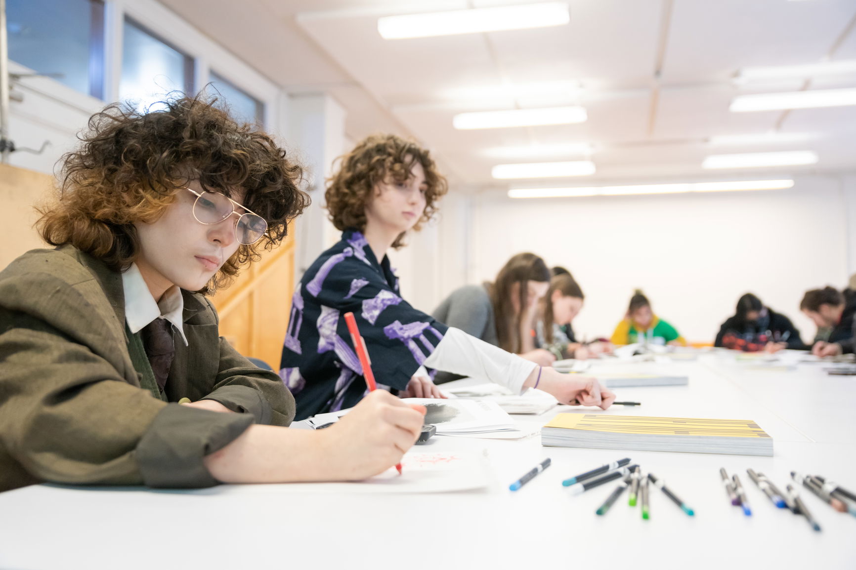 a photo of two students drawing in a classroom