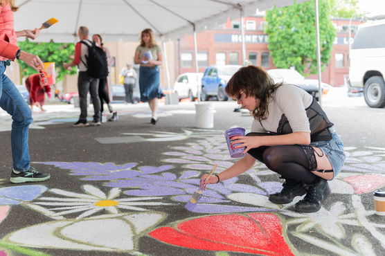 a person paints on concrete under a large tent