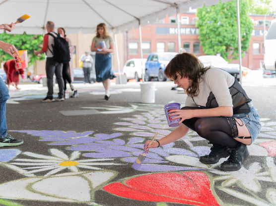 a person paints on concrete under a large tent