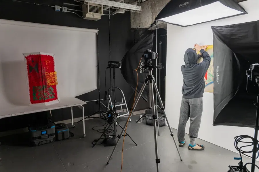Photographer setting up lighting and backdrop in a studio for a shoot.