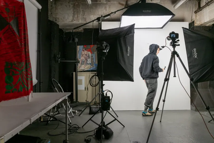 A photographer in a studio setup with lighting and equipment, preparing for a shoot.
