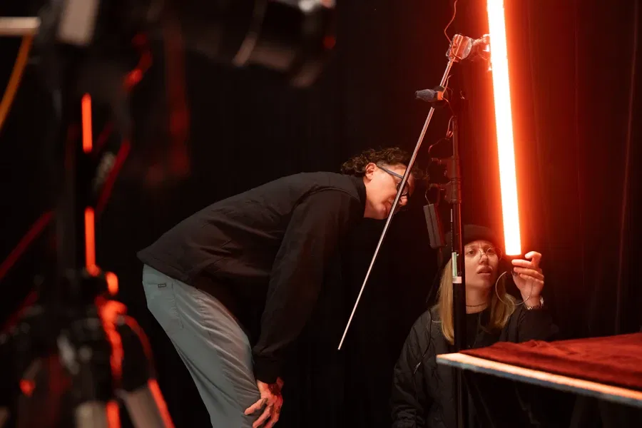 Two individuals adjusting a bright light in a studio setting.