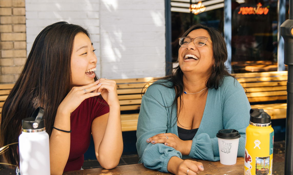 Two students laughing over coffee.