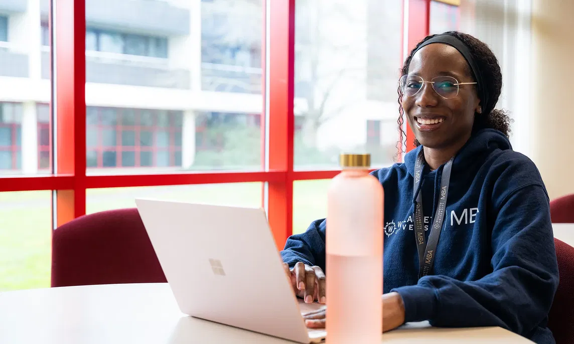 A Willamette University MBA student sitting at a table with a laptop computer.