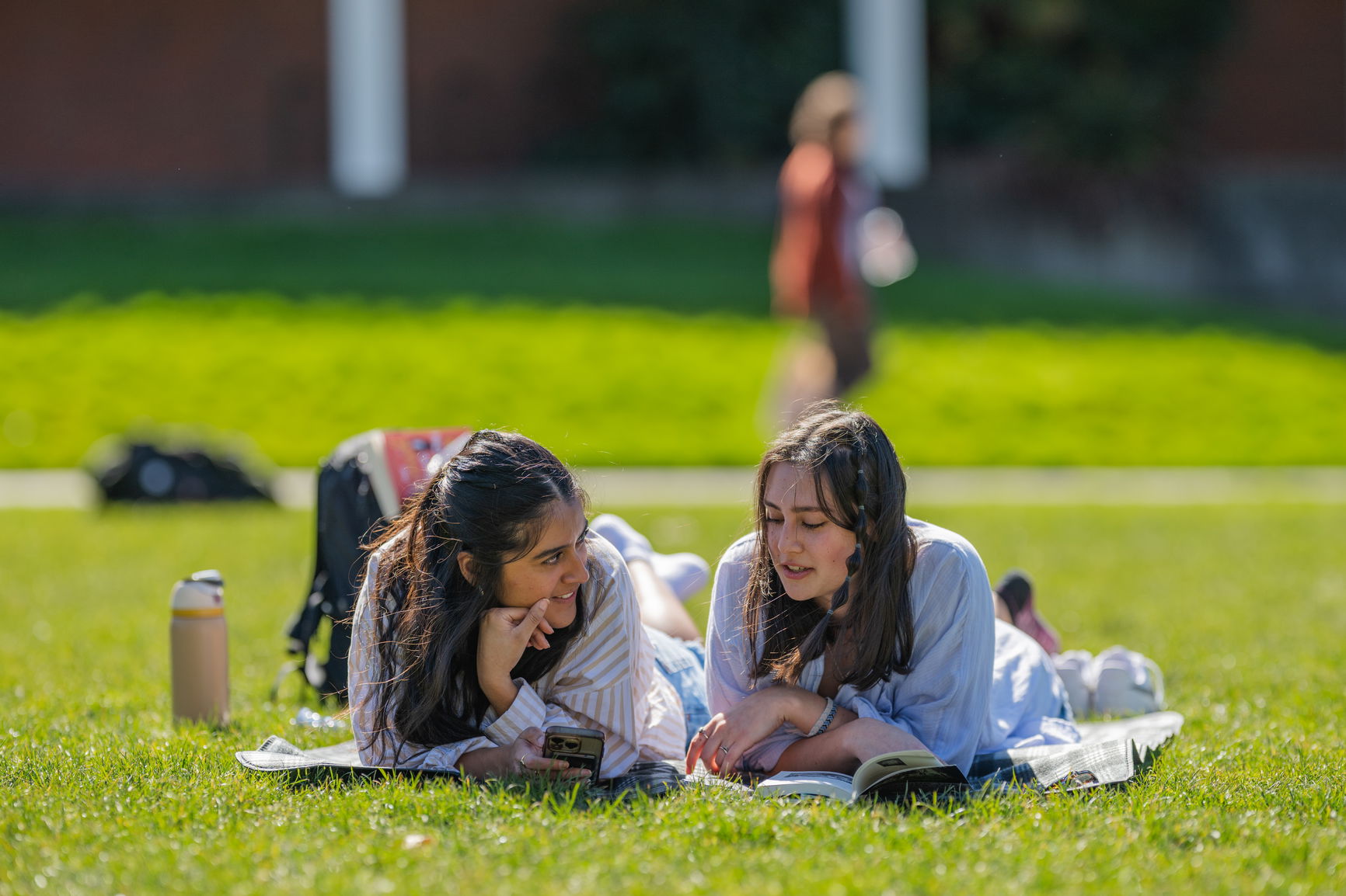 Two students laying in the grass and chatting