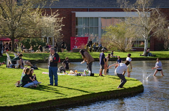 People enjoying sunshine on the grass surrounding Mill Stream in Salem