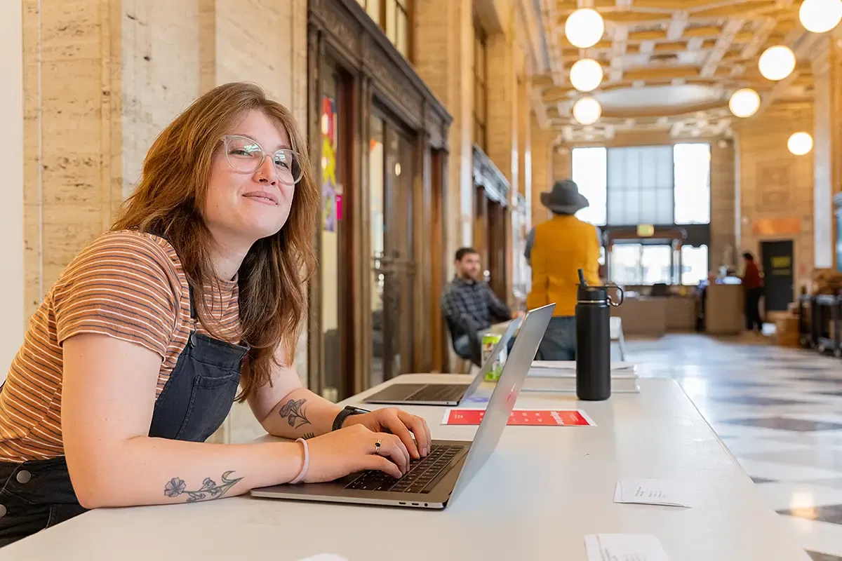 A PNCA student sitting at a table in the school lobby.