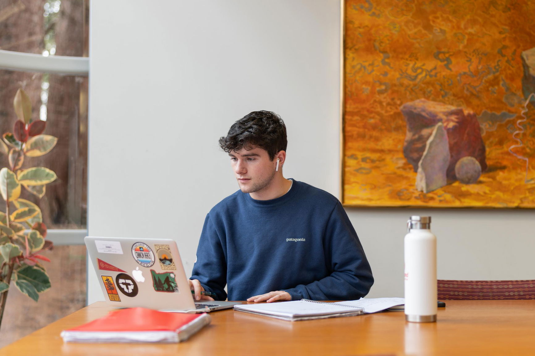 A student sitting at the table with a laptop in the library. 