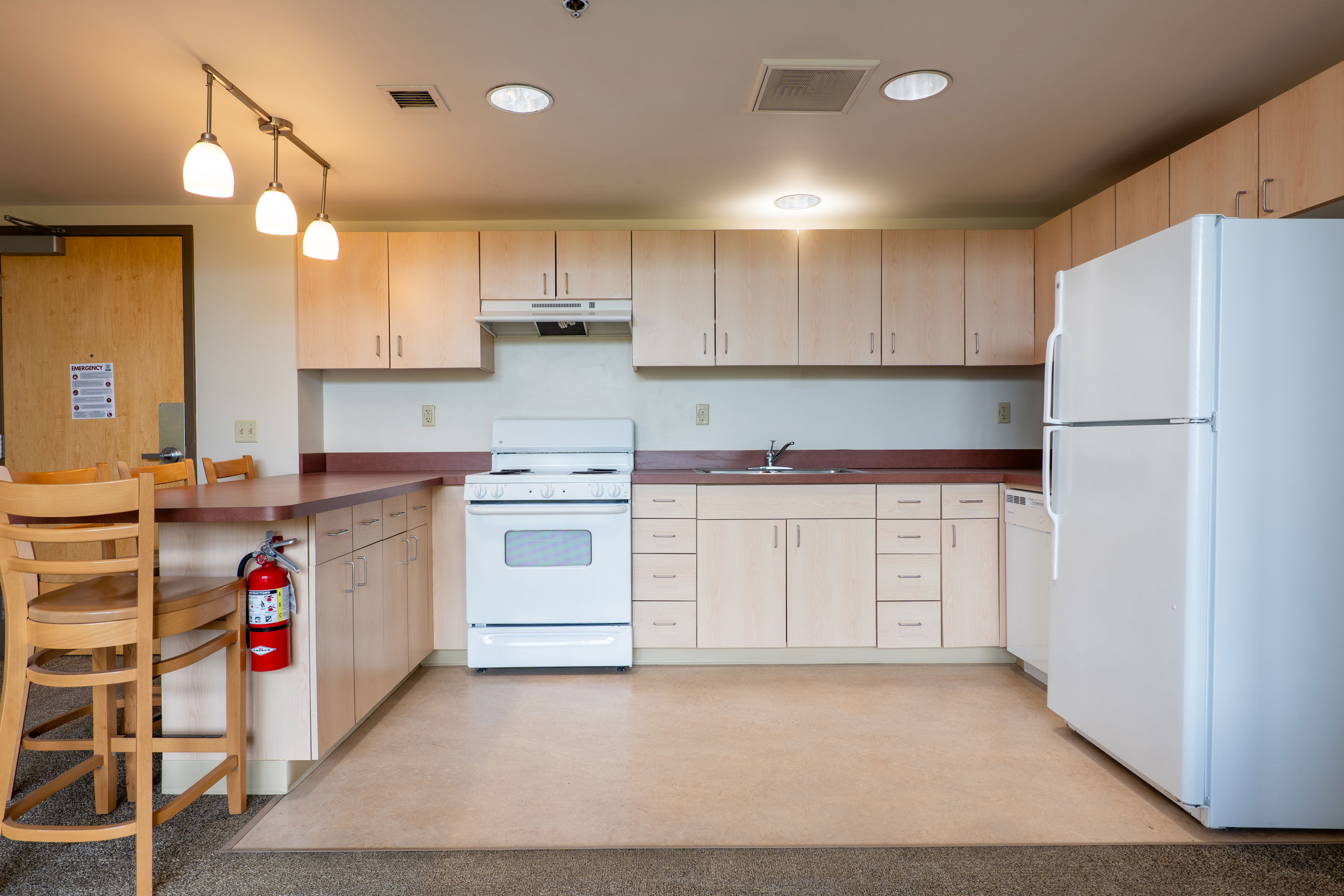 Apartment kitchen showing cabinets, sink area, dishwasher, oven and stove, and fridge and freezer