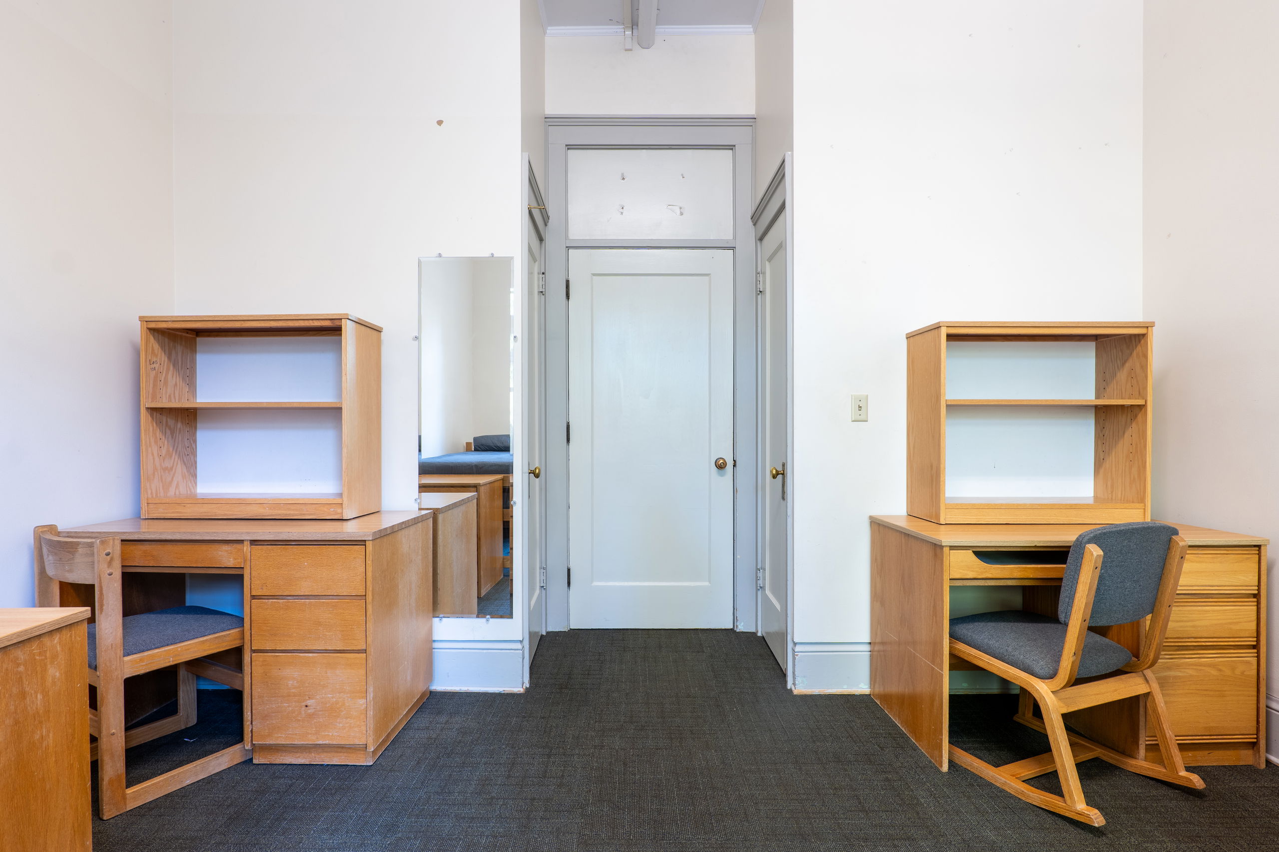 Double room showing desks, dressers, and chairs and the door to the residential room