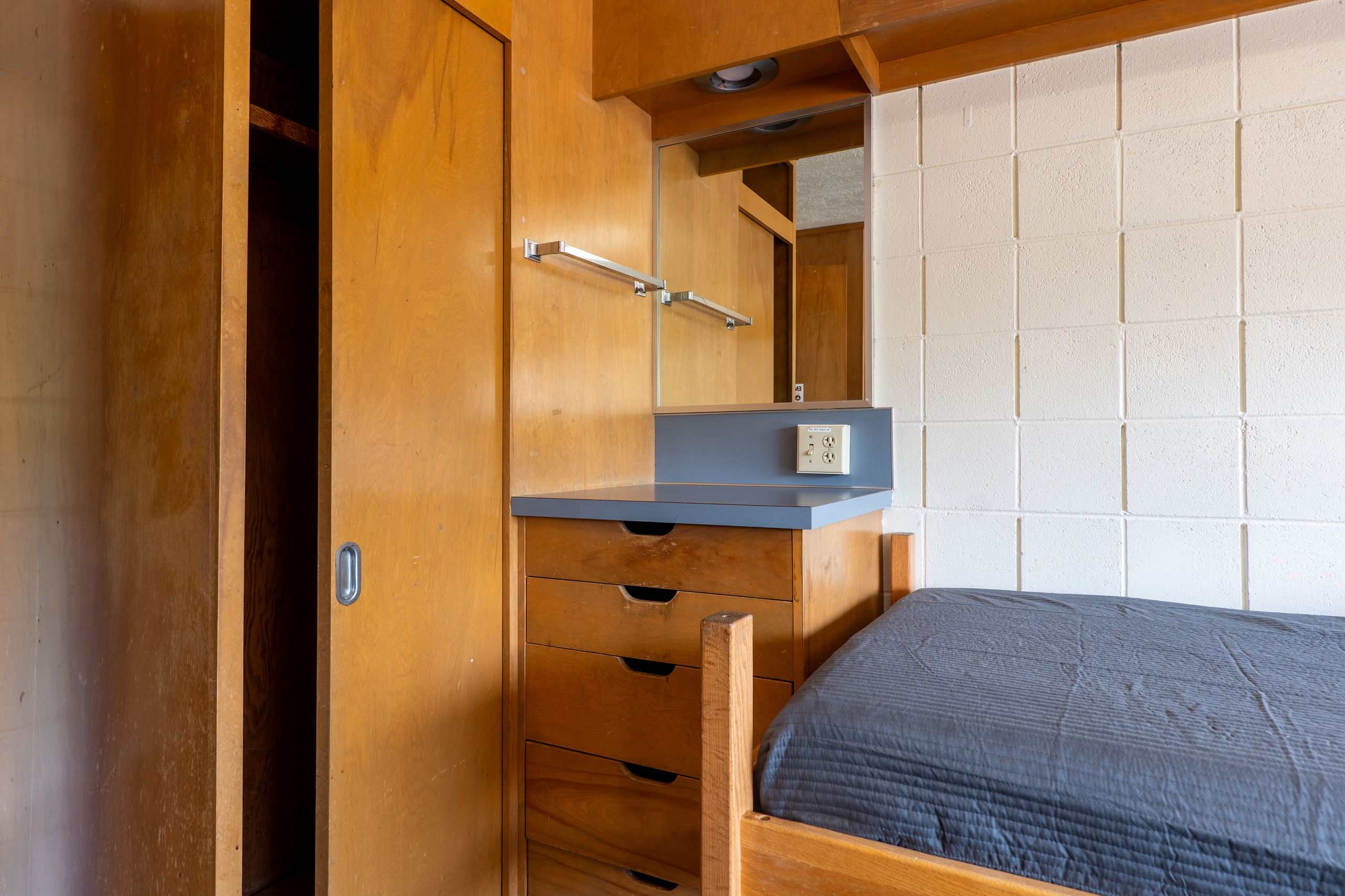 one side of double room showing a sink, cabinet and drawers, a closet, and a bed