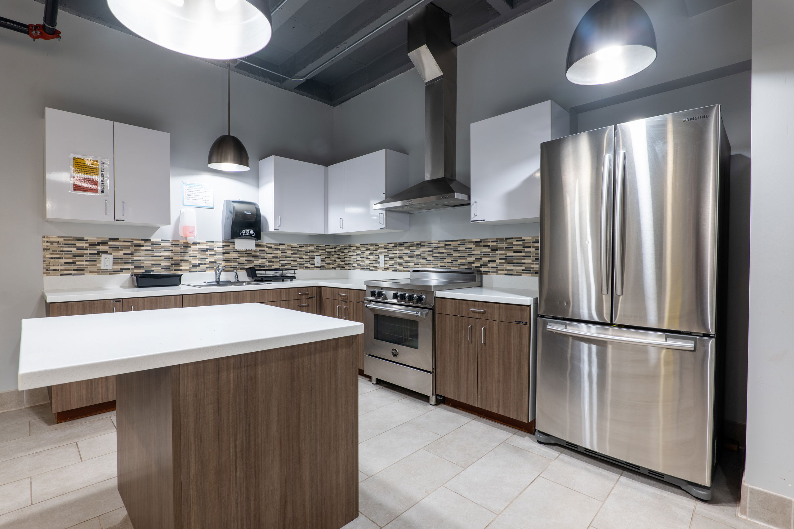 Communal kitchen showing middle island, fridge and freezer, oven and stove, and sink and counter area