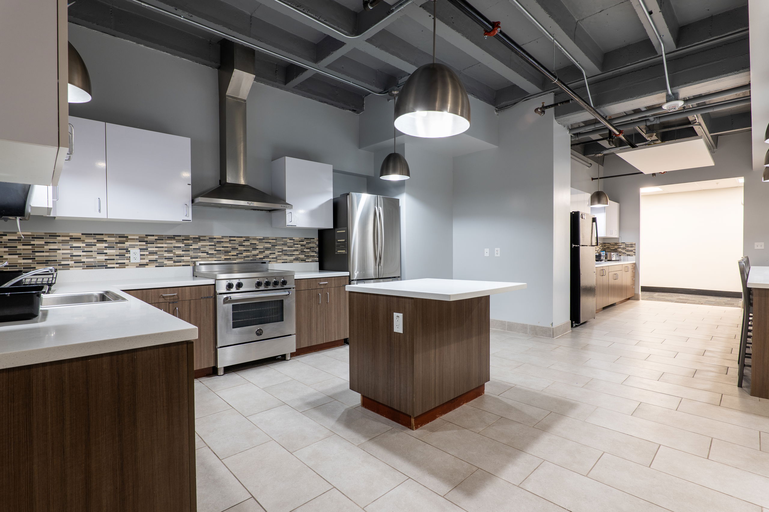 Communal kitchen showing middle island, fridge and freezer, oven and stove, and other counter space