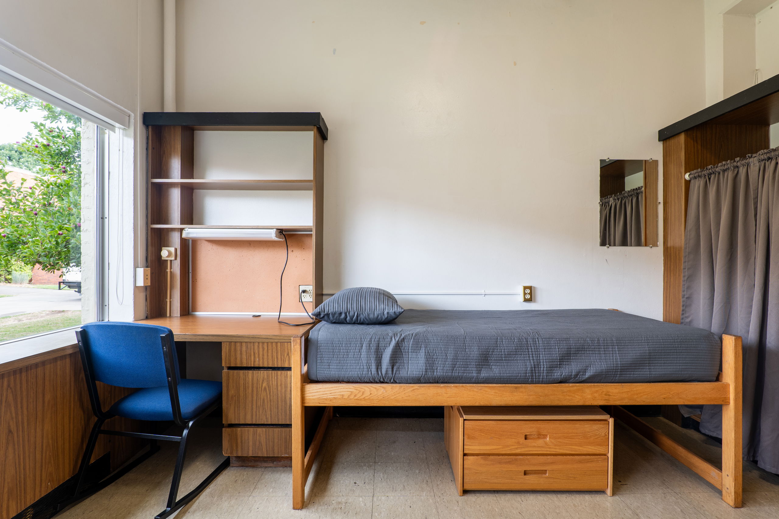 One side of a double room with a desk, bed, closet, and chair