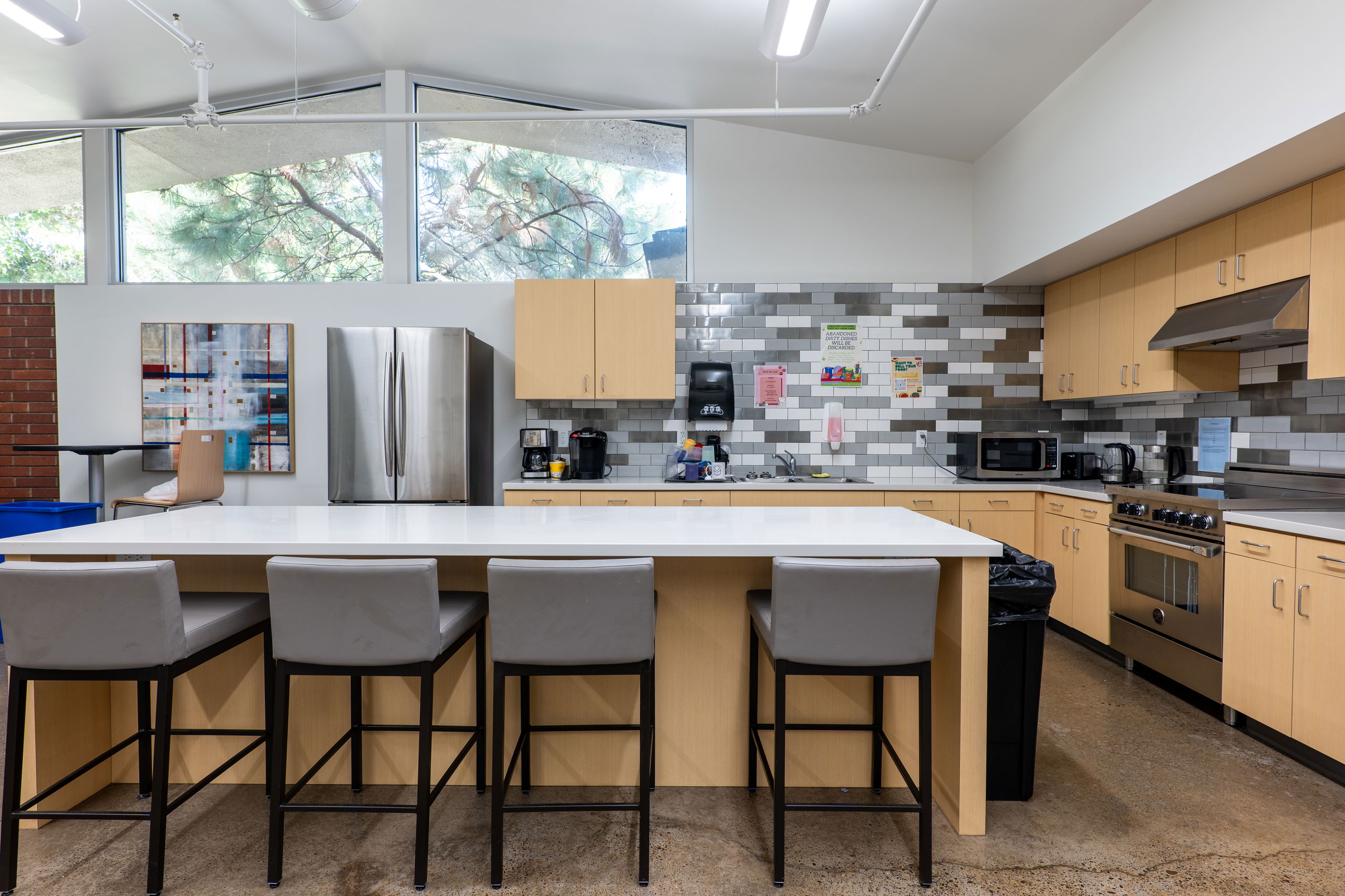 York common area kitchen with a middle island and stools, oven and stove, fridge and freezer, and sink and counter spaces