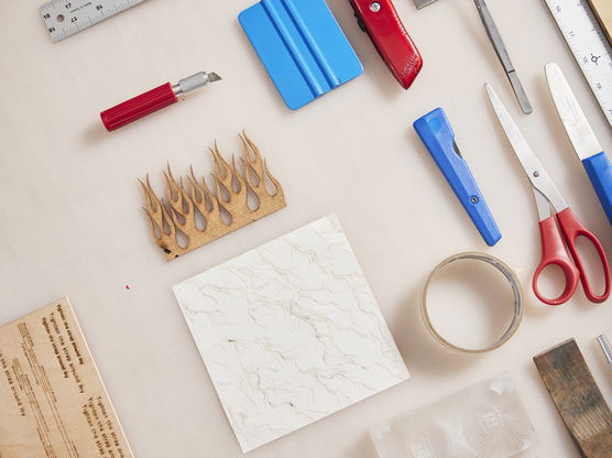 A collection of writing and drawing implements including various scissors, knives and rulers lay artfully arranged on a table