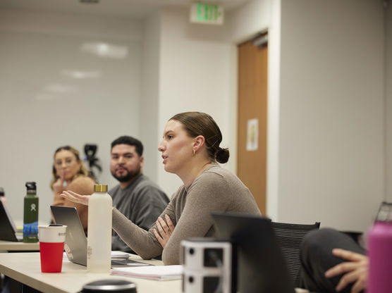 Several Willamette MBA students sit at a table in an Atkinson Graduate School of Management classroom, discussing schoolwork