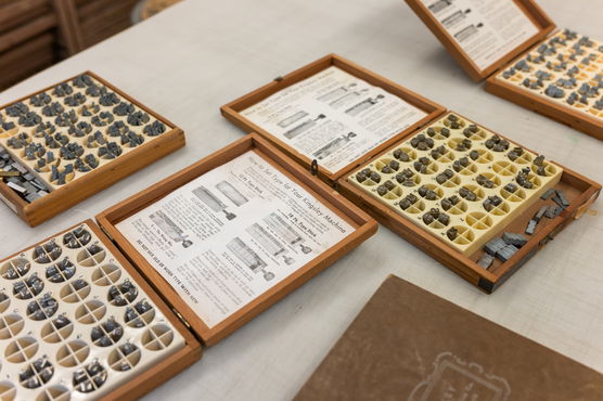 Several open boxes of pieces for a Kingsley Hot Foil Stamping Machine sit on a table in PNCA's printmaking studio