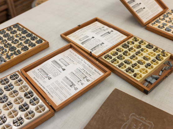 Several open boxes of pieces for a Kingsley Hot Foil Stamping Machine sit on a table in PNCA's printmaking studio