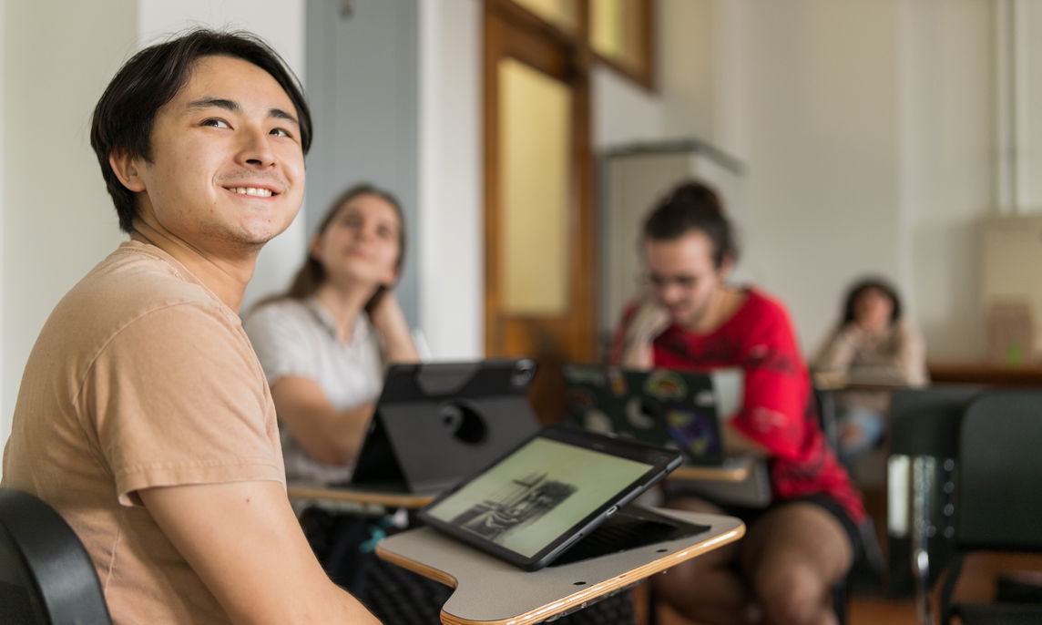 PNCA students sit at desks in a classroom with tablets in front of them, listening to a Language Arts lecture