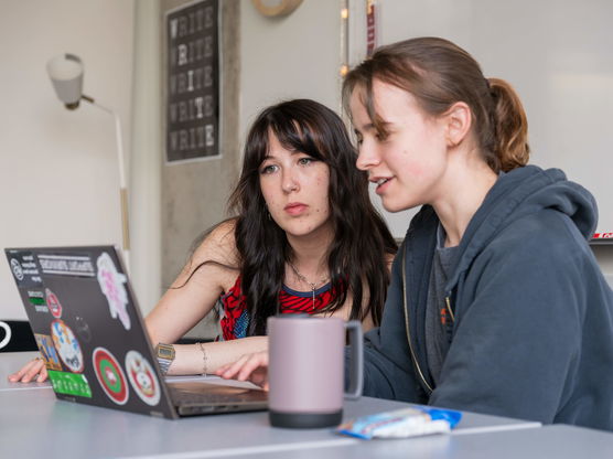 Two Willamette students work together in front of a laptop at the Writing Center