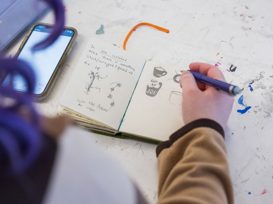 A PNCA student draws coffee mugs in a small notebook with a pencil during a 2-D design class