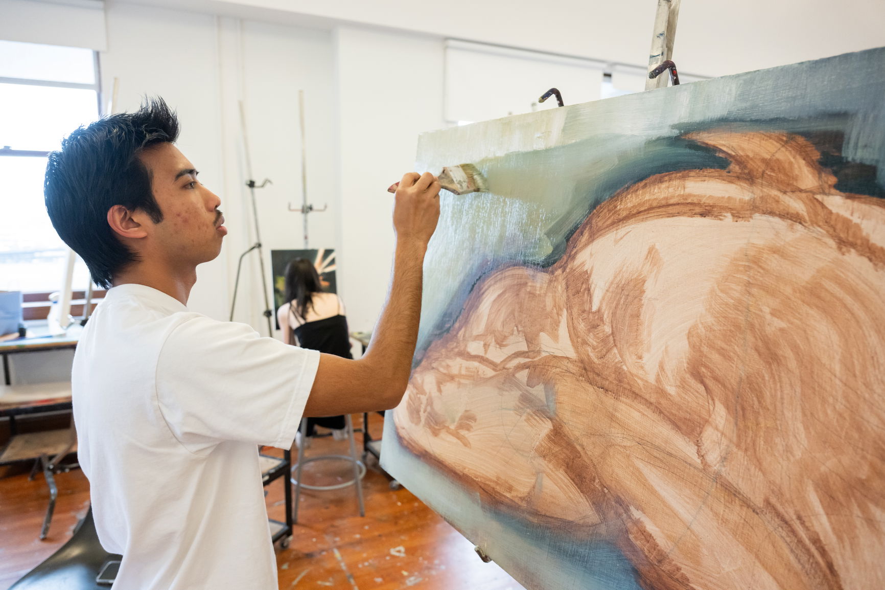 A PNCA student paints on a large canvas in the campus studio