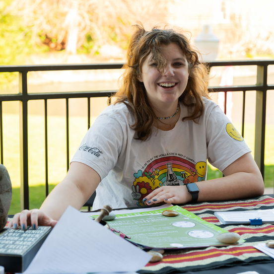 A Willamette student wearing a rainbow t-shirt tabling for student activities on Bearcat Day