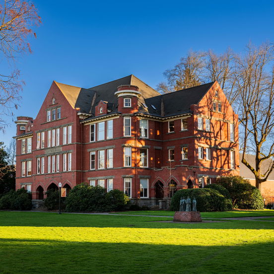 Willamette University's Eaton Hall, a Gothic-style red brick building on a large green lawn with a sculpture in front