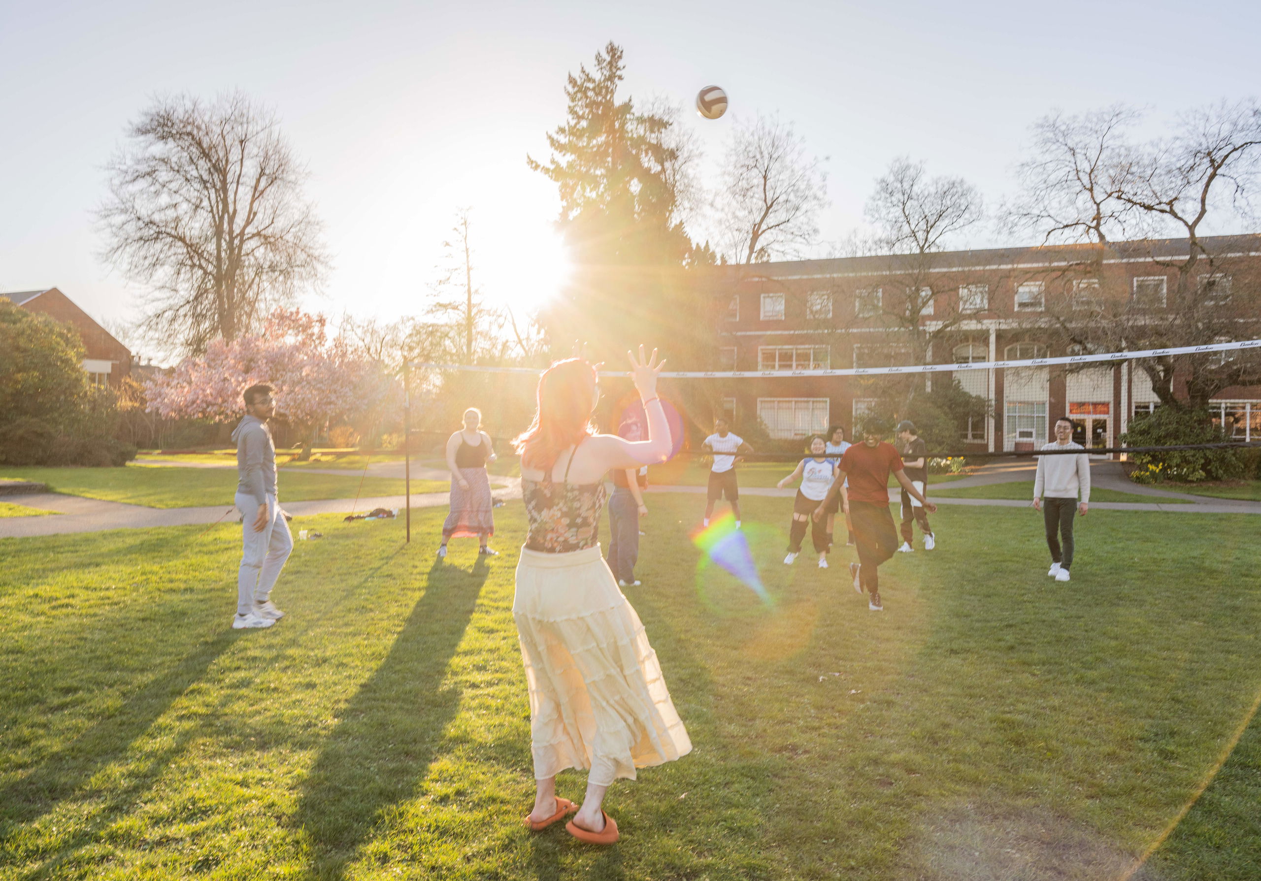 A group of Willamette students play volleyball together on a sunny day on campus