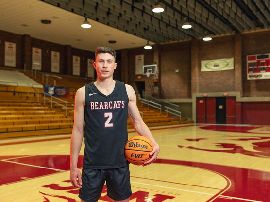 Willamette student Jack Boydell stands on a basketball court holding a basketball and wearing a Bearcats jerseyfpo