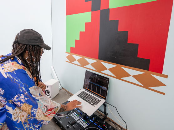 A PNCA grad student examines a laptop in front of a large wall painting as part of a Visual Studies critique